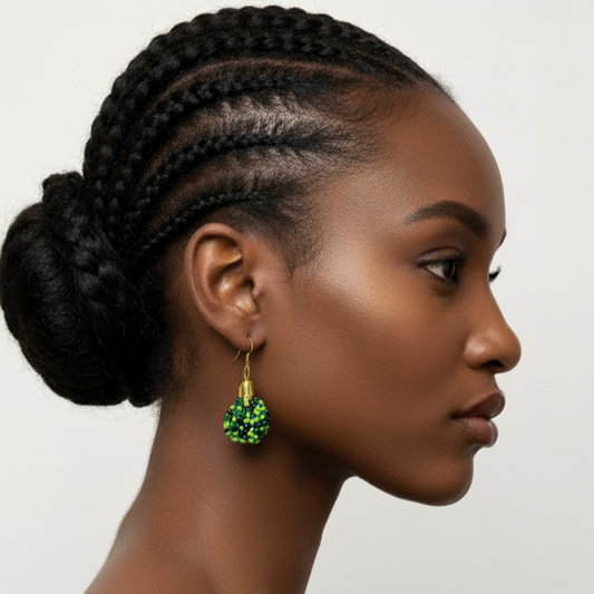 Woman with braided hair wearing small green beaded earrings on a plain background