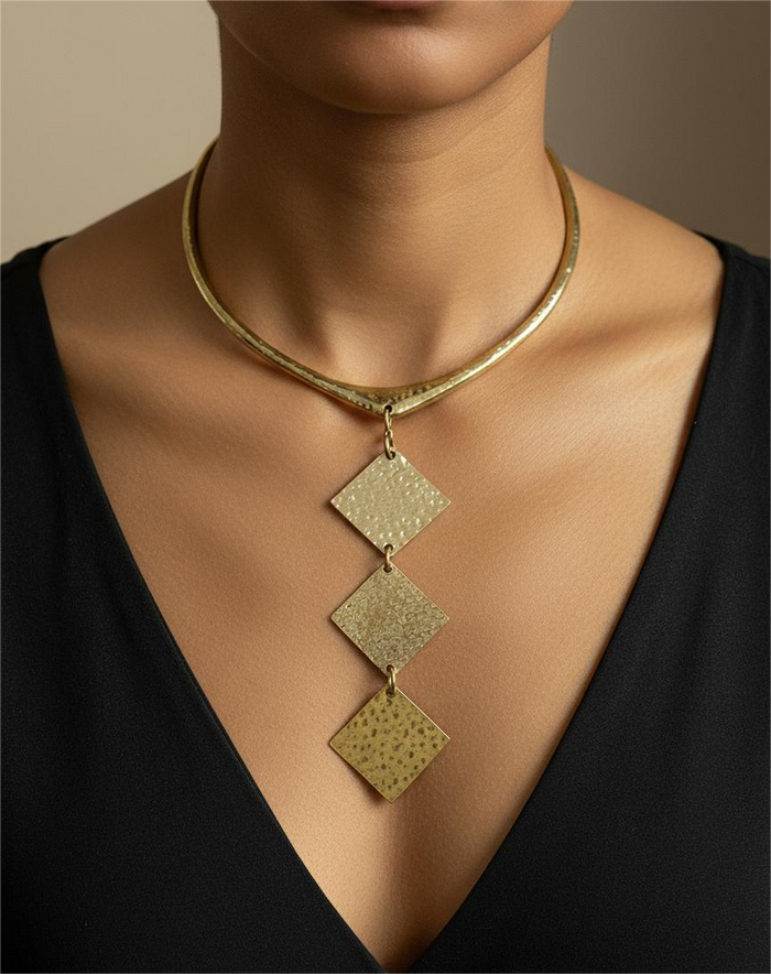 Gold necklace with three square pendants on a model wearing a black top.