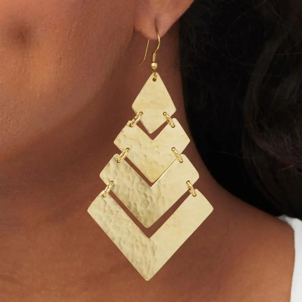 A close-up of an ear dawning a gold earring in a shepherd hook design.