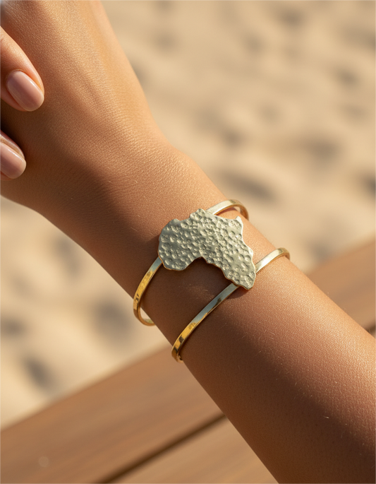 A brass cuff withan African brass pendant on a wrist with a blurred background