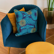 A colorfully patterned blue and yellow pillow case cover sitting in an arm chair.