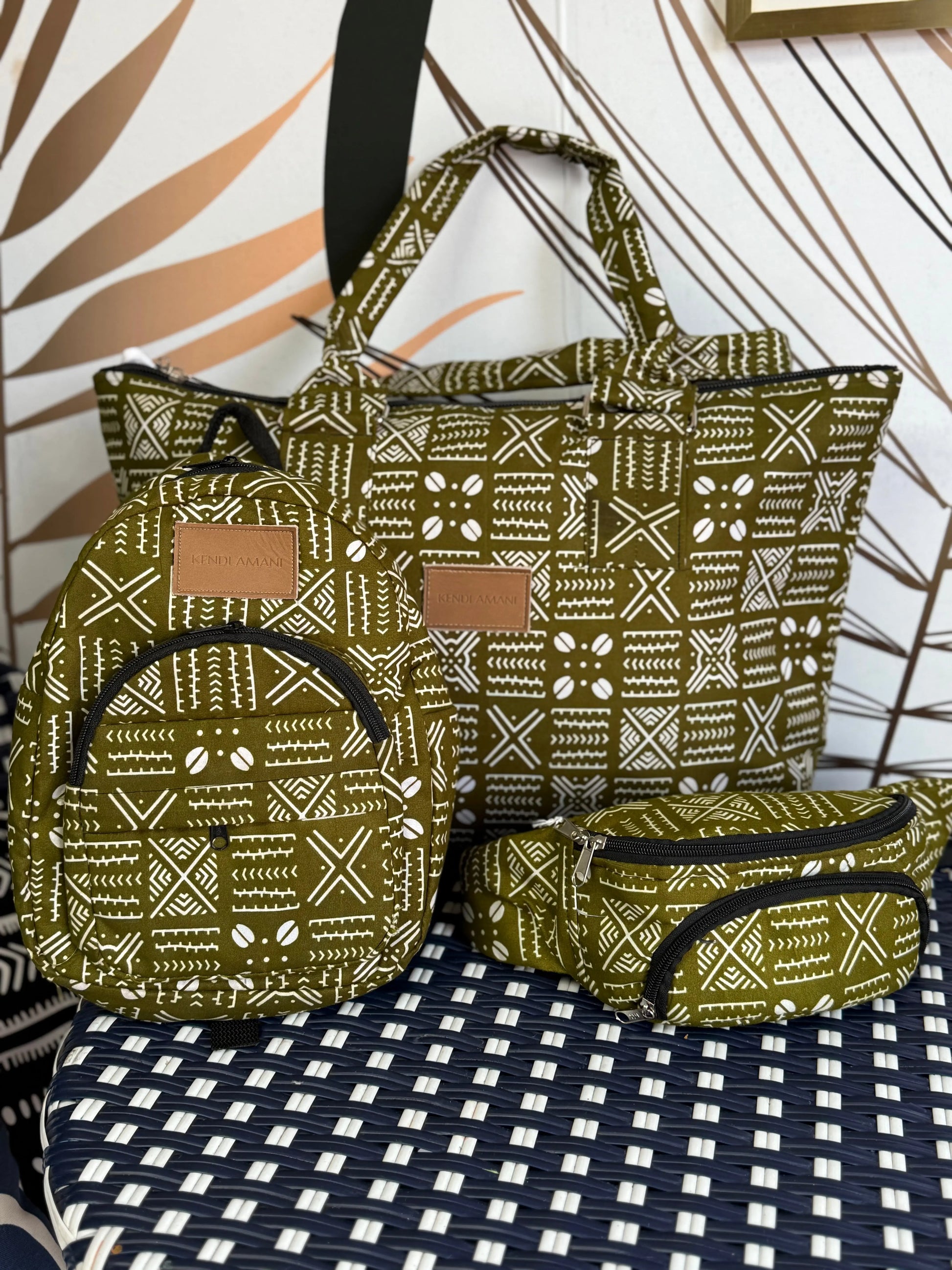 Set of green patterned bags including a backpack, tote bag, and pouch on a checkered surface.
