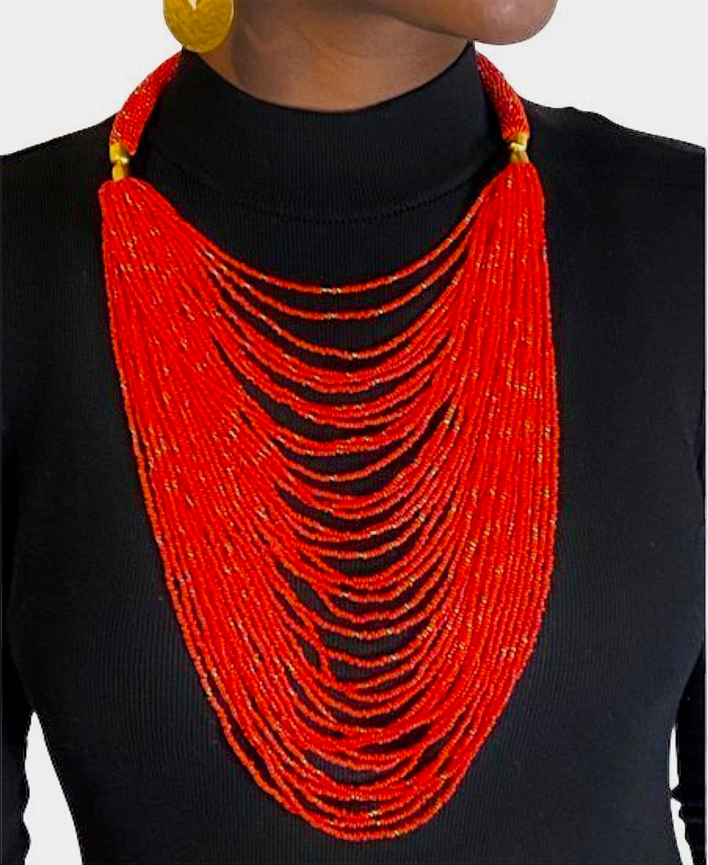 A woman wearing a red beaded necklace with gold accents.