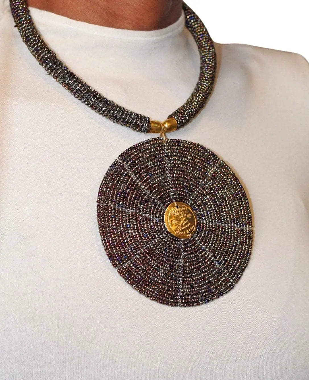 A model wearing a circular black beaded necklace with gold accents.
