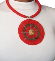 A woman wearing a red circular beaded necklace with gold accents.