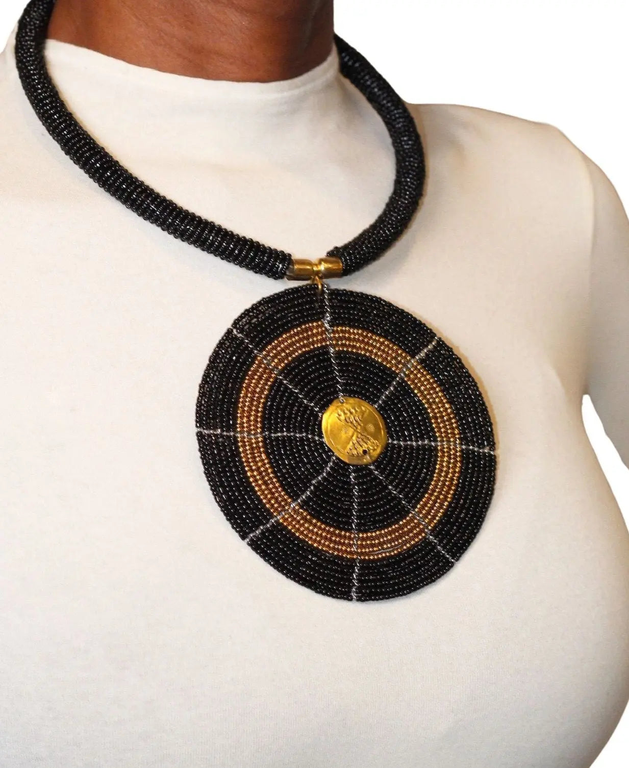 A woman wearing a black circular beaded necklace with gold accents.
