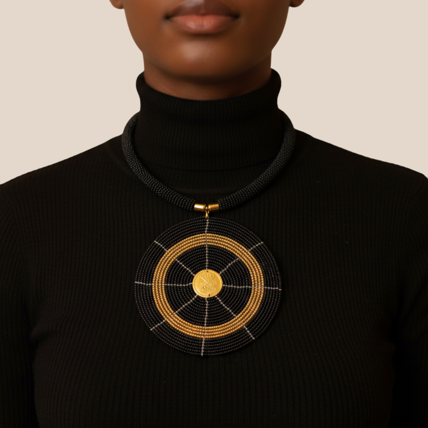 Person wearing a black turtleneck with a gold and black circular beaded pendant necklace.