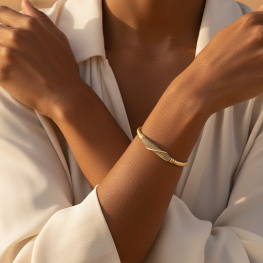 Woman in a white outfit with a gold bracelet against a desert background