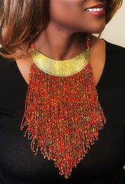 A woman wearing a red and gold beaded necklace.