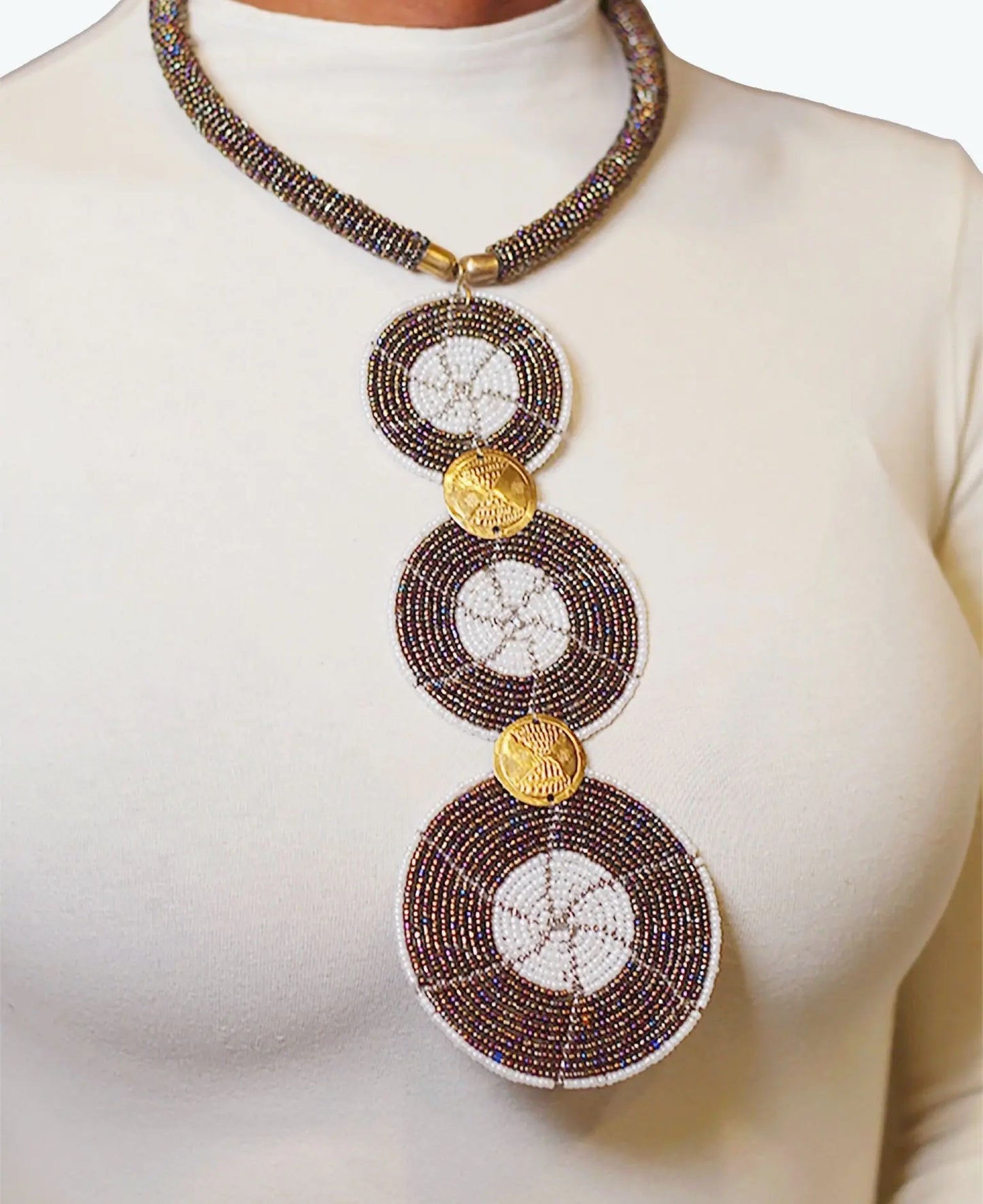 A woman wearing a long circular black and white beaded necklace with gold accents.