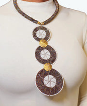 A woman wearing a long circular black and white beaded necklace with gold accents.