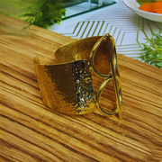 Gold cuff bracelet on a wooden surface