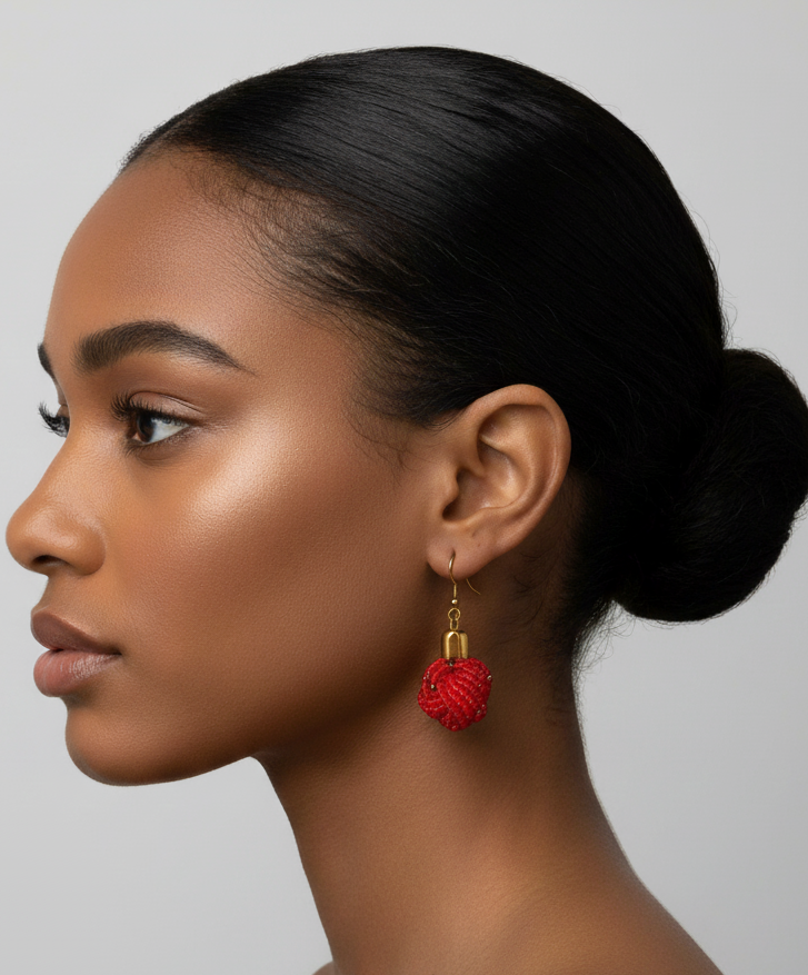 Woman with a bun wearing red earrings against a neutral background