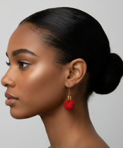 Woman with a bun wearing red earrings against a neutral background