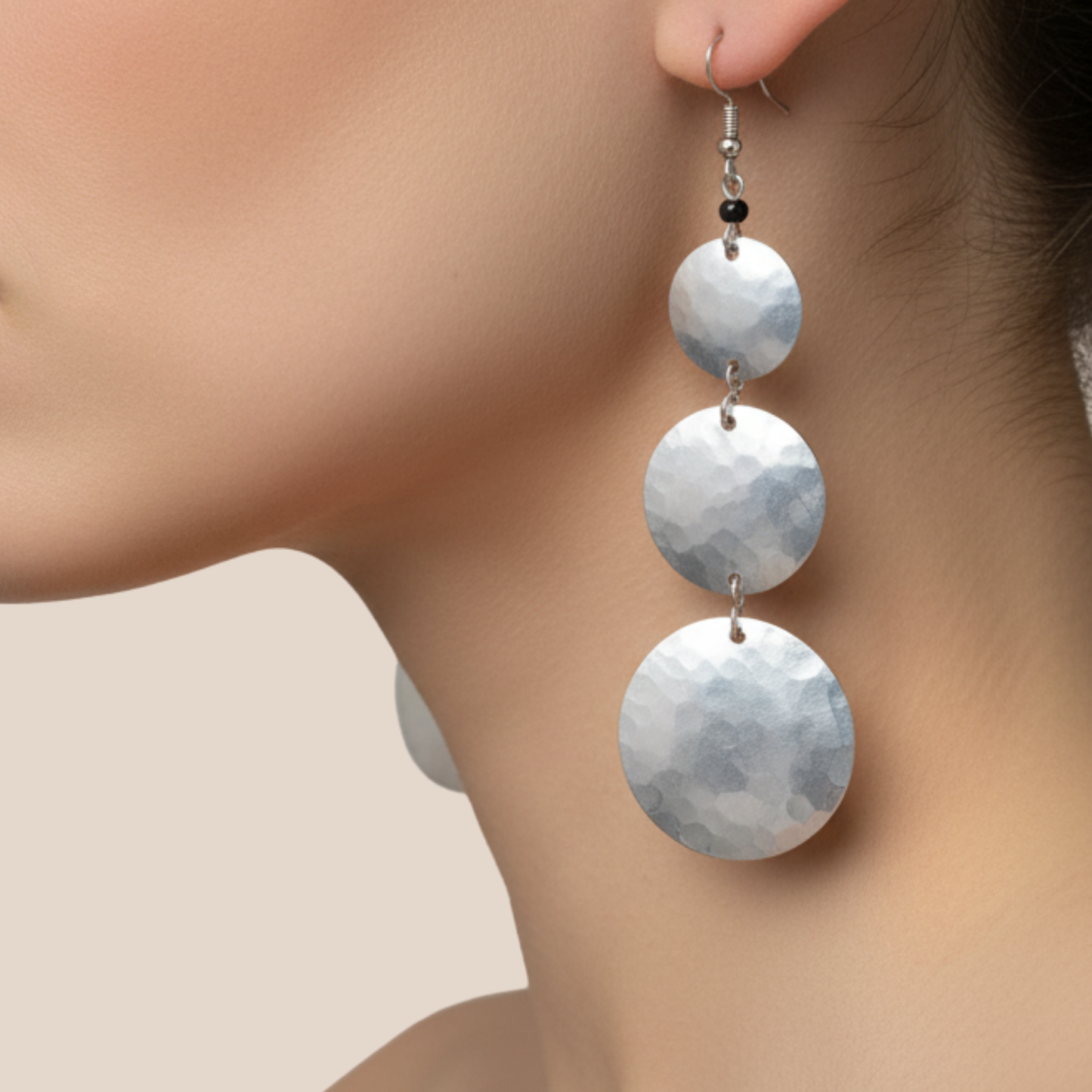 Close-up of a woman wearing a pair of silver earrings with circular designs.