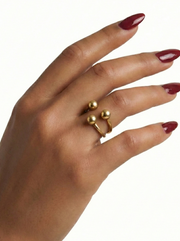 Hand wearing a gold ring with red nail polish on a white background