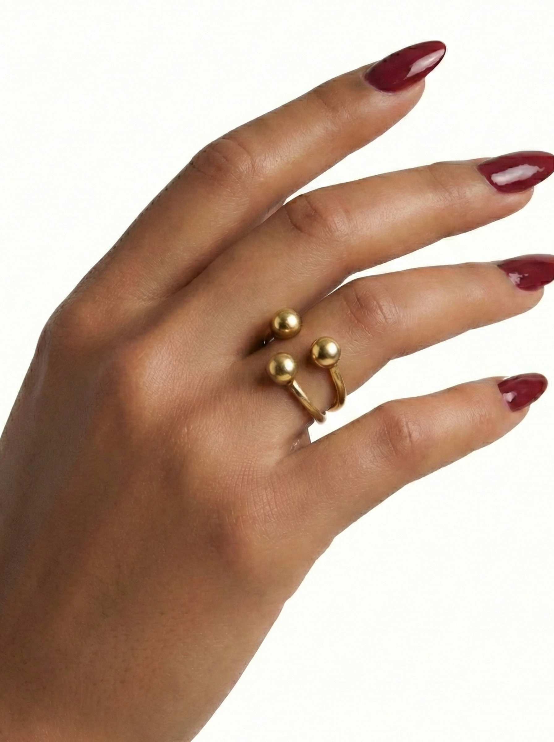 Hand wearing a gold ring with red nail polish on a white background