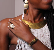 A person's wrist wearing a gold-plated cuff bracelet with a subtle hammered texture.