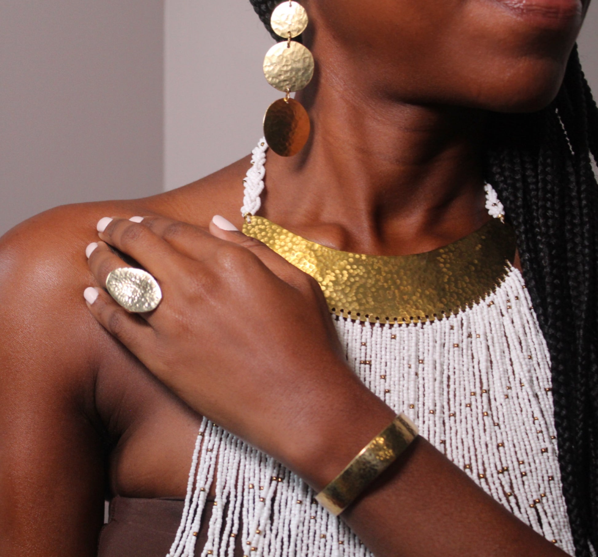 A person's wrist wearing a gold-plated cuff bracelet with a subtle hammered texture.