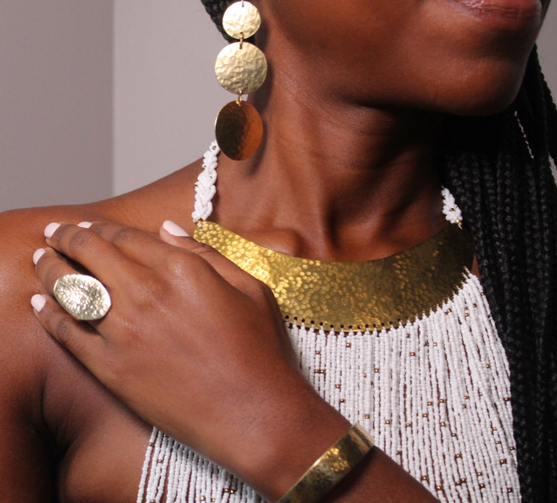 A person's wrist wearing a gold-plated cuff bracelet with a subtle hammered texture.