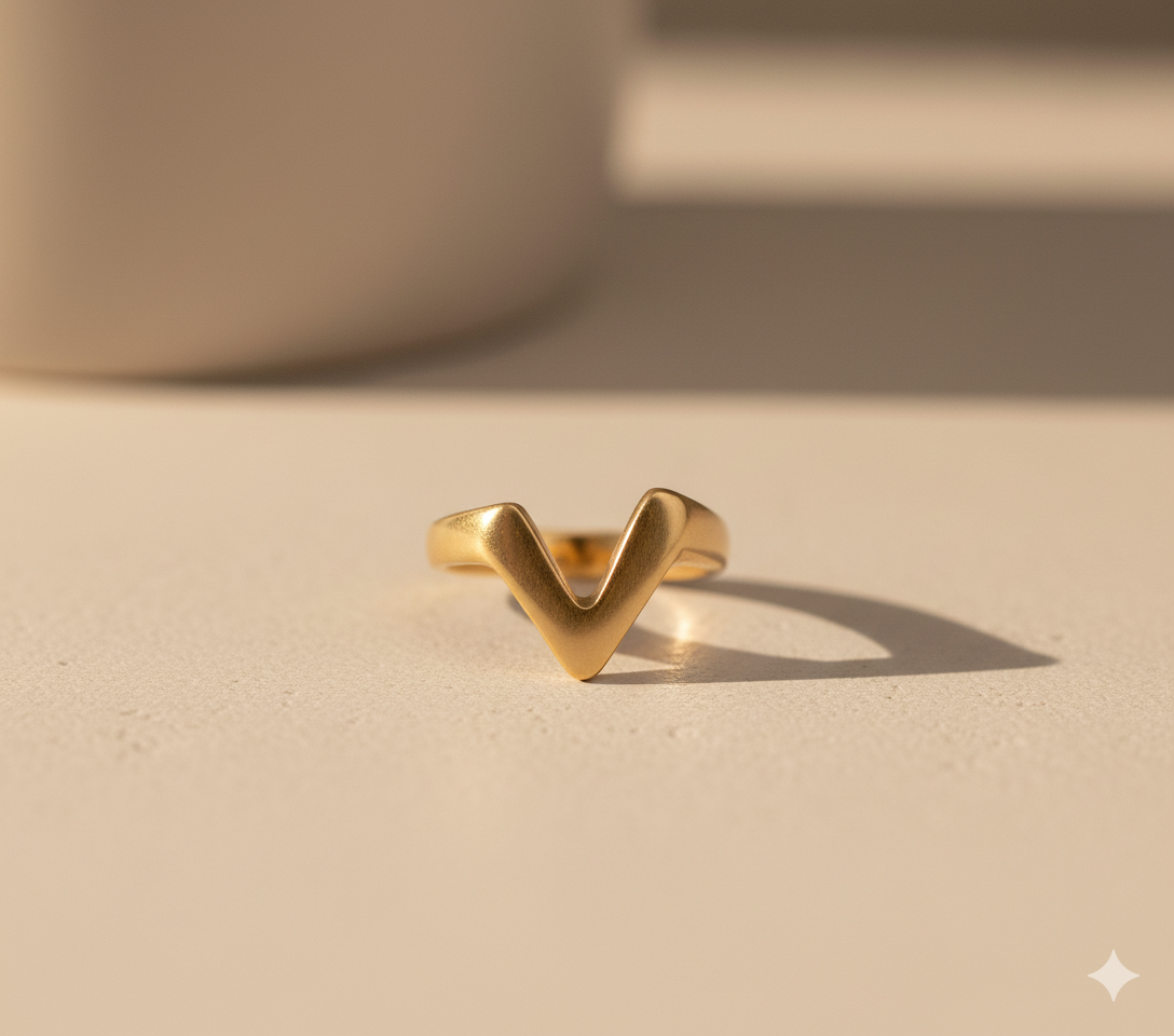 Gold 'V' shaped ring on a beige background