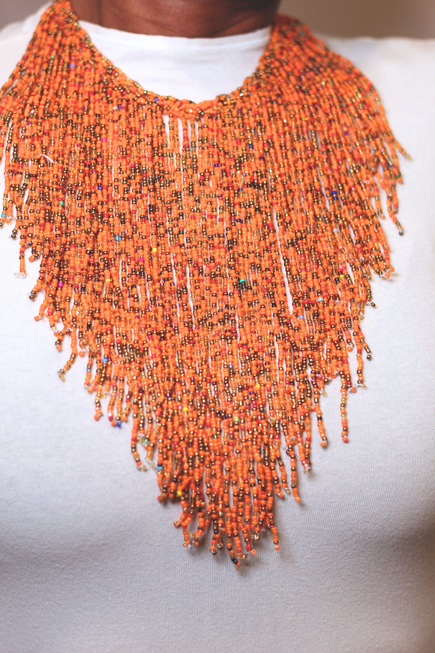 A woman wearing an orange beaded necklace with gold accents.