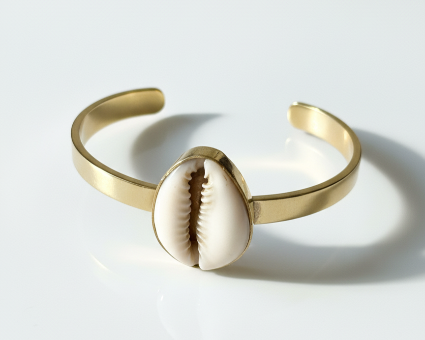 Brass bracelet with a shell charm on a light gray background