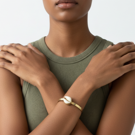 Woman wearing a brass bracelet on a neutral background