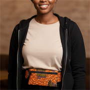 Woman wearing a black jacket and beige top with an orange patterned belt.