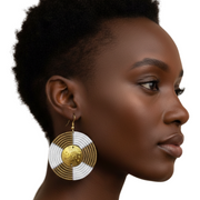 A woman wearing a large white & gold earring on a white background