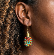 Close-up of an ear wearing a colorful beaded earring with curly hair.