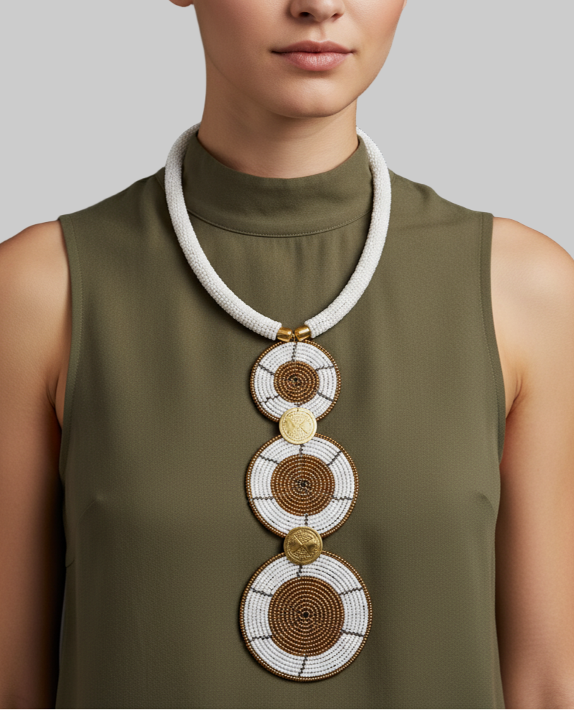 Woman wearing a long, decorative necklace with circular patterns on a dark background