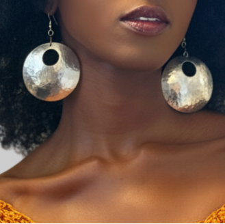 Woman wearing a mustard yellow crochet top with large statement earrings against a neutral background